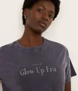 Remera oversized gris con efecto desteñido y estampa frontal con la frase "Glow Up Era".