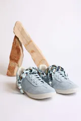 Zapatillas bajas de gamuza celeste con cordones y pañuelos estampados atados a los cordones.