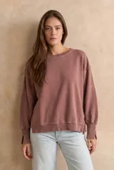 Buzo de algodón peinado color marrón con efecto lavado, de corte oversize, cuello redondo y mangas largas con puños anchos. Presenta costuras visibles y aberturas laterales en los puños y el ruedo.
