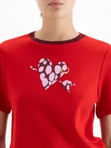 Remera de jersey pesado color blanco, con cuello redondo en contraste negro y estampa central de un corazón con diseño animal print atravesado por una flecha.