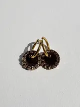 Aros de acero quirúrgico con dije circular de resina rosa y borde de strass dorados.