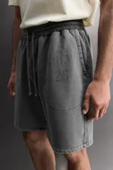 Short tipo jogger de algodón con interior afelpado, cintura elástica ajustable con cordón, bolsillos frontales y bolsillo trasero. Presenta un efecto lavado y estampado gráfico a contraste en el frente.