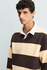 Sudadera tipo polo de corte regular, color gris claro, con cuello solapa en color blanco y cierre frontal de botonadura oculta. Presenta mangas largas con puños y ruedo en rib.