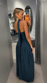 Vestido largo color verde oscuro, de corte strapless con escote recto y falda larga con caída fluida. Incluye una gargantilla a juego.