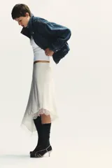 Falda midi de satén color blanco, de corte asimétrico y con encaje en el ruedo.