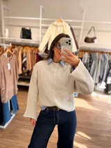 Sweater de punto canalé en color beige, con diseño de cuello bote, mangas largas amplias y corte crop. Presenta una textura acanalada vertical que recorre toda la prenda.
