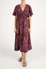 Vestido largo con estampado animal print abstracto en tonos bordó y rosado. Presenta escote en V, mangas cortas con volados y cintura elástica fruncida.