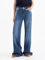 Jeans de denim azul con diseño clásico de cinco bolsillos, silueta semi oxford de tiro medio-alto, entallada en caderas y muslos con botamanga acampanada. Presenta lavado en azul medio con contrastes y desgastes focalizados.