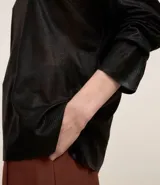 Blusa de punto color dorado, de acrílico y viscosa, con escote redondo, manga larga y sisa raglán. Tiene una malla con lámina metálica.