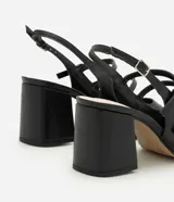 Zapato estilo Mary Jane de color negro, confeccionado en poliuretano con diseño cerrado y puntera cuadrada. Presenta tres tiras cruzadas en el empeine con hebillas metálicas ajustables, tira trasera con hebilla y taco bloque ancho.
