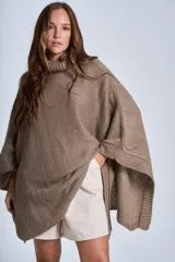 Poncho tejido color beige, con cuello alto y corte asimétrico.