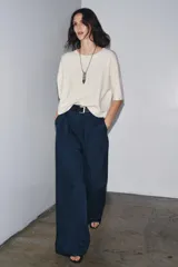 Jersey de punto color crema, confeccionado en 100% lana, con cuello redondo y mangas cortas anchas, de calce amplio.