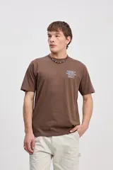 Remera de algodón marrón de manga corta, con cuello redondo y detalle estampado pequeño en el pecho.