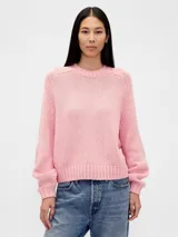 Buzo de tejido de punto en color rosado, con cuello redondo, mangas largas con puños acanalados y dobladillo inferior también acanalado. Presenta un diseño de corte relajado.