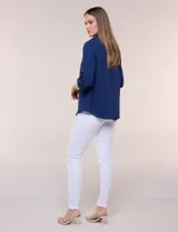 Blusa verde de calce holgado y caída fluida, confeccionada en tejido tipo crepé. Cuenta con cuello camisero con solapa, escote en V y cierre parcial al frente con tres botones metálicos. Las mangas son largas con puños abotonados.