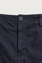 Bermuda de denim color azul marino, de corte relaxed fit con pliegues frontales, bolsillos laterales y cierre frontal con cremallera y botón.