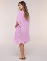 Vestido playero tipo túnica de corte holgado color rosado, confeccionado en tejido semi transparente con textura sutilmente arrugada. Cuenta con escote en V pronunciado, mangas estilo kimono de caída fluida y aberturas laterales en el ruedo irregular.