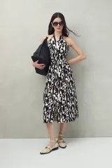 Vestido midi con estampado abstracto en blanco y negro, escote halter y falda acampanada con abertura frontal.