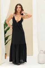 Vestido largo negro de lino con tirantes ajustables con lazo y diseño escalonado con vuelo en la parte inferior.