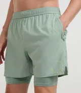 Bermuda deportiva para hombre, color verde menta, con short de compresión integrado. La bermuda exterior es suelta y tiene un pequeño logo estampado en el muslo izquierdo.