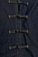 Cazadora de denim azul oscuro, de corte entallado, cuello redondo y manga larga. Cuenta con cierre frontal con alamares y costuras pespunteadas en contraste.