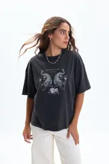 Remera negra de manga corta, corte holgado y diseño boxy. Presenta un estampado frontal de dos tigres enfrentados rodeados de flores, con la frase "BRILLENT POUR TOUJOURS PARIS, 1986".