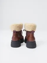 Borcegos de caña baja con diseño robusto, confeccionados en una combinación de gamuza y cuero sintético en tonos verde oliva. Presentan suela track de goma dentada en color suela, cordones al tono con ojalillos amarillos y cuello acolchado para mayor confort.