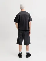 Remera negra de manga corta y cuello redondo, de corte holgado. Cuenta con estampado frontal de estilo deportivo que incluye la inscripción "LA GRACIOSA", un parche circular con diseño de sol y el logo de la marca.