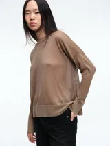 Sweater de tejido fino y semitransparente con hilo brillante. Presenta cuello redondo, hombros caídos y mangas largas amplias con un ajuste relajado y caída fluida.