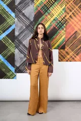 Camisa de gabardina marrón con estampa a cuadros y rayas diagonales, diseño plisado en el frente y detalle de aplique floral de plumas en el cuello.