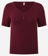 Blusa de pijama bordó de ribana, con textura acanalada, escote en V con abertura frontal de botones y mangas cortas.
