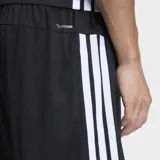 Short deportivo Adidas de corte clásico, color negro con las icónicas tres rayas blancas laterales. Cuenta con cintura elástica, bolsillos laterales con cierre y logo de la marca en la pierna.