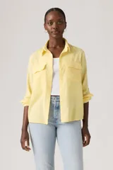 Camisa de lino color amarillo pastel, con bolsillos frontales con solapa, mangas largas remangadas y cierre frontal con botones.