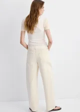 Jeans de corte holgado y tiro medio color beige claro, con diseño de pernera ancha y bolsillos clásicos.