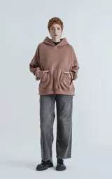 Hoodie oversize de corte crop en color marrón, confeccionado en frisa gamuzada de algodón. Presenta capucha forrada, bolsillo tipo canguro frontal y puños y ruedo acanalados.