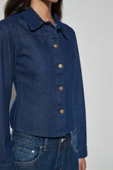 Campera corta de denim azul oscuro con cuello camisero, mangas largas y cierre frontal de botones metálicos dorados.