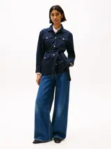 Campera azul marino estilo militar con cuello inglés, cierre de botones dorados con el escudo TH en relieve, cinturón anudable, cuatro bolsillos delanteros con botón, puños con botón y logo metálico de Tommy Hilfiger en el puño.