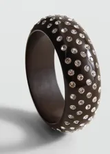 Pulsera rígida de resina color negro, con diseño abovedado y apliques de cristales brillantes distribuidos por toda la superficie.