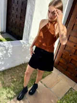 Top halter confeccionado en cuero color camel, con diseño sin mangas, espalda descubierta y ajuste mediante tiras.