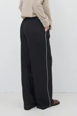 Pantalon de corte recto y pierna ancha, confeccionado en tela tipo denim color azul oscuro, con costuras a contratono y detalle de abertura lateral en el ruedo.