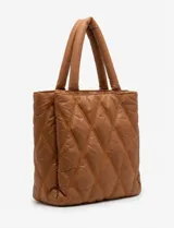 Cartera de eco cuero color marrón, con diseño capitoneado en rombos de gran relieve. Cuenta con un compartimento principal con cierre, amplios bolsillos laterales con botones imantados, asa de mano fija y correa larga regulable y removible. El forro interno es textil a tono con compartimentos organizadores.