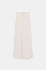Falda larga color crudo, de tiro alto con cintura elástica tipo nido de abeja y cordón ajustable.