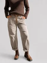 Pantalón de corte recto y holgado en color beige, con cintura elástica y dobladillo en los tobillos. Incluye un cinturón de cuero sintético con tachas metálicas decorativas.