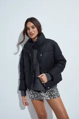 Campera puffer de nylon color marrón oscuro, con cuello alto, cierre frontal y puños elásticos. Diseño acolchado de volumen ligero.
