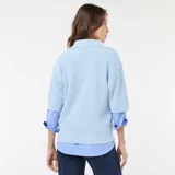 Sweater de punto en color celeste, con cuello en pico y mangas cortas. Presenta un diseño de tejido acanalado y corte holgado.