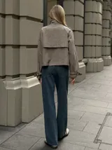 Chaqueta corta de corte recto con estampado de pata de gallo en tonos marrones y beige. Presenta cuello alto, cierre frontal cruzado con botones y detalles de trabillas en los hombros y puños.
