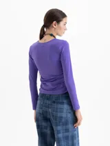 Top de lycra color violeta, con cuello redondo, mangas largas y detalle de frunces laterales en la cintura que aportan movimiento a la prenda.