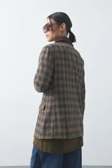 Blazer de corte relajado con estampado de cuadros tipo pied de poule en tonos rojizos y verdes. Presenta solapas clásicas en color azul oscuro y estructura definida.