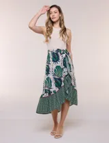 Vestido midi de diseño combinado con torso de punto acanalado beige, sin mangas y cuello redondo, unido a una falda fluida de corte asimétrico con estampado botánico y geométrico en tonos verdes y azules, y detalle de lazo ajustable en la cintura.