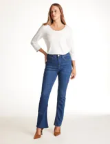 Jean de tiro alto con corte bootcut, ajustado en cadera y muslos con una sutil apertura desde la rodilla. Presenta diseño clásico de cinco bolsillos, cierre con botón y costuras en contraste. Su diseño posterior incluye costuras estratégicas para un efecto de realce en la silueta.